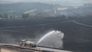 En 2022 après l'incendie des monts d'Arrée en Bretagne, un tracteur arrose le sol calciné avec une citerne.